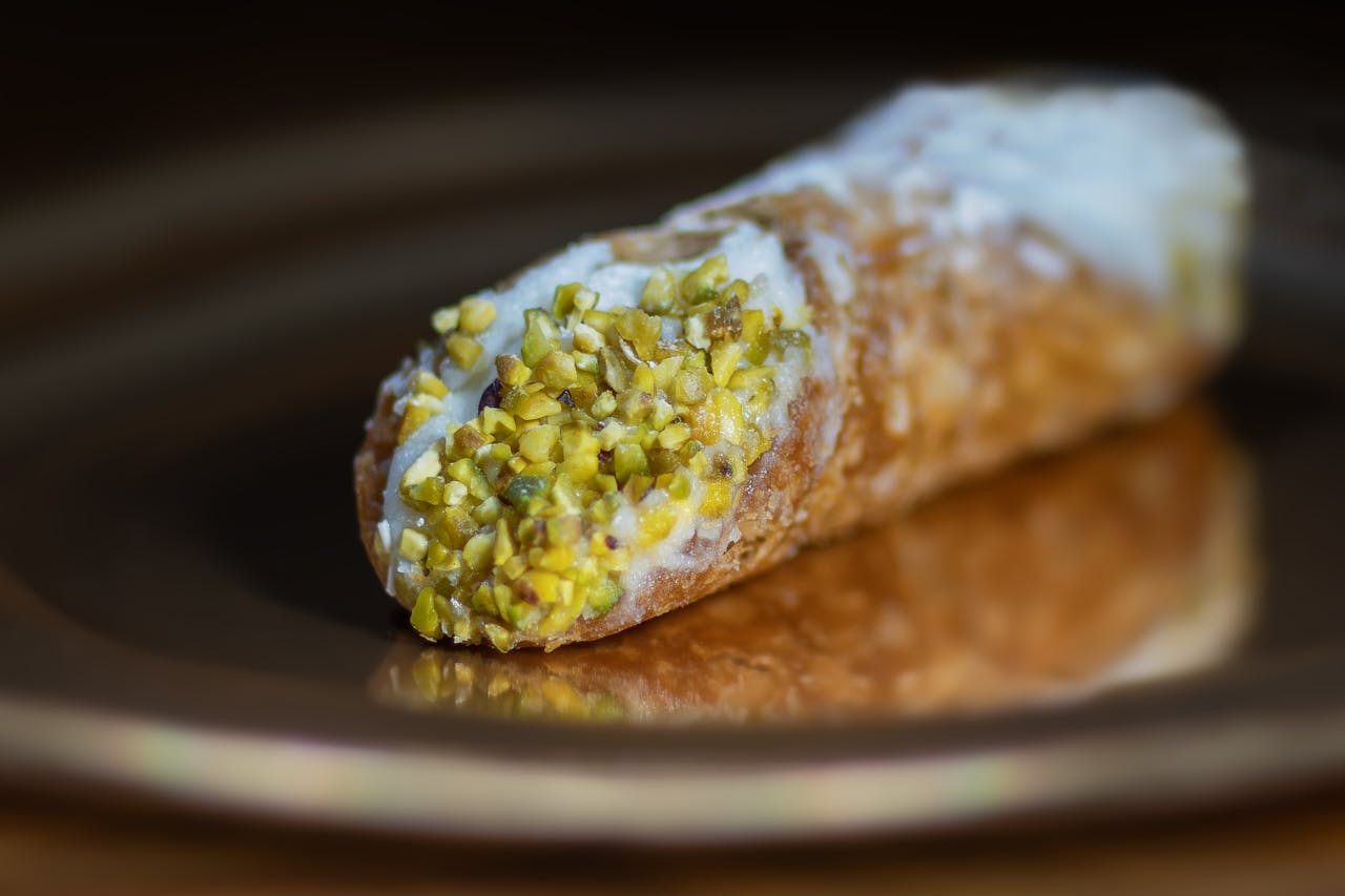 Close-up of a pistachio-topped cannoli pastry, showcasing the texture and vibrant colors.